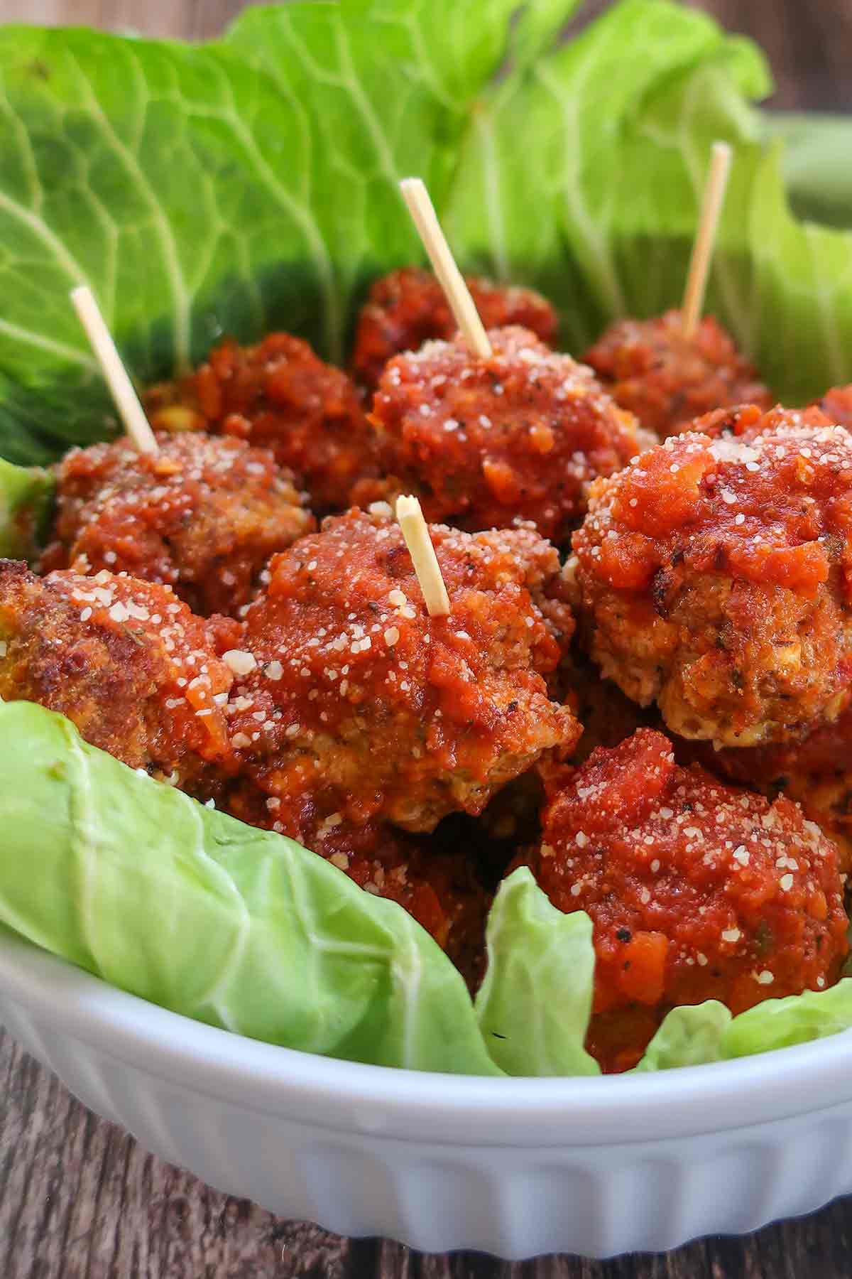 close up of italian gluten free meatballs in a bowl lined with cabbage leaf