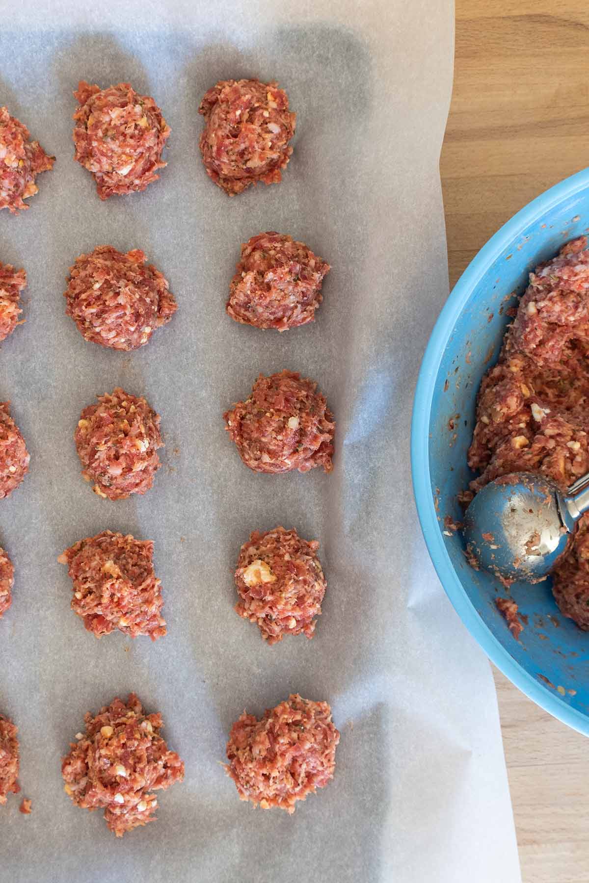 uncooked meatballs on a baking sheet lined with parchment paper