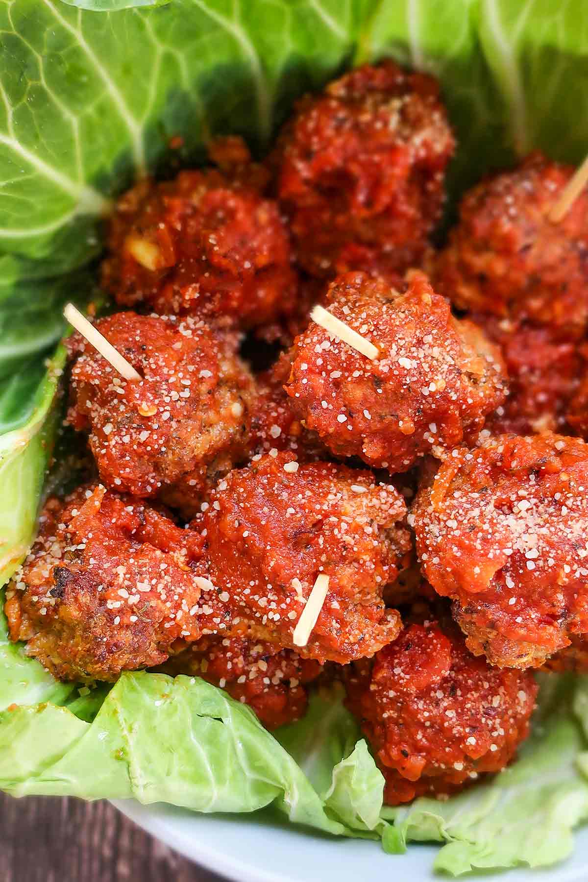 baked gluten free meatballs in a bowl lined with a cabbage leaf