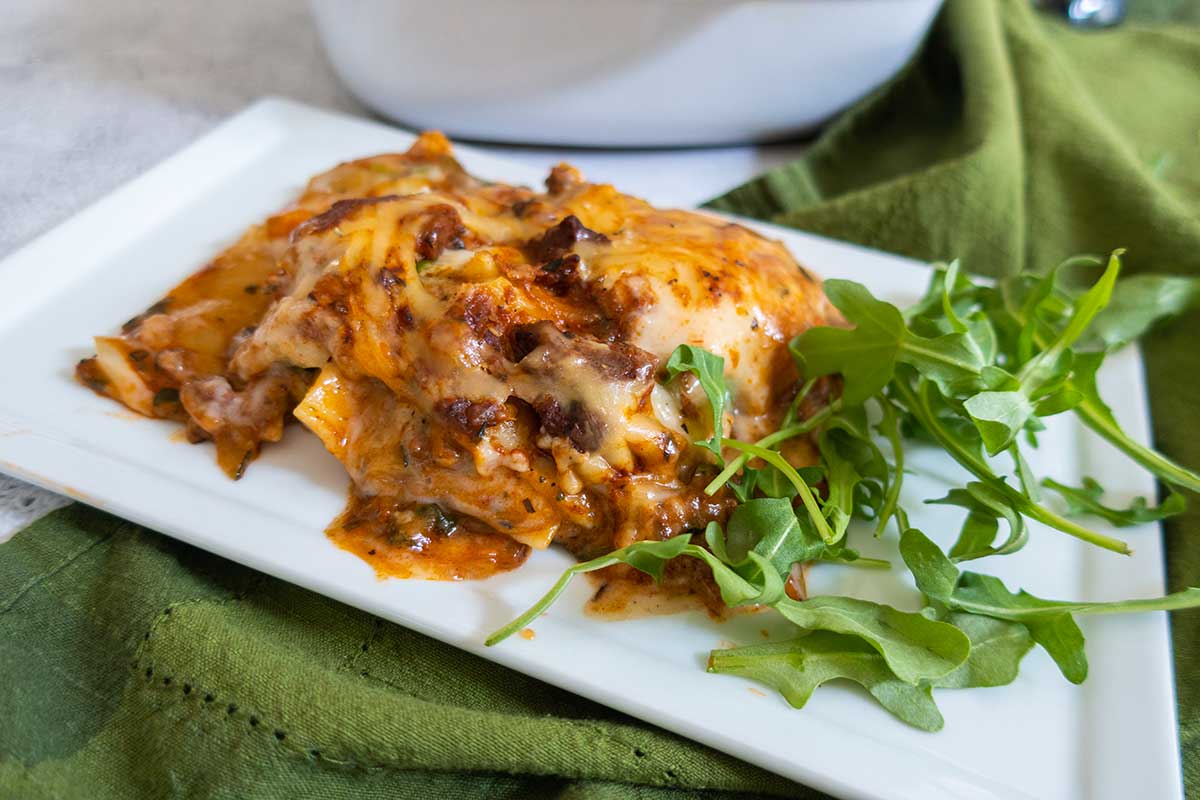 slice of dairy free creamy lasagna on a plate with fresh Basil, gluten free