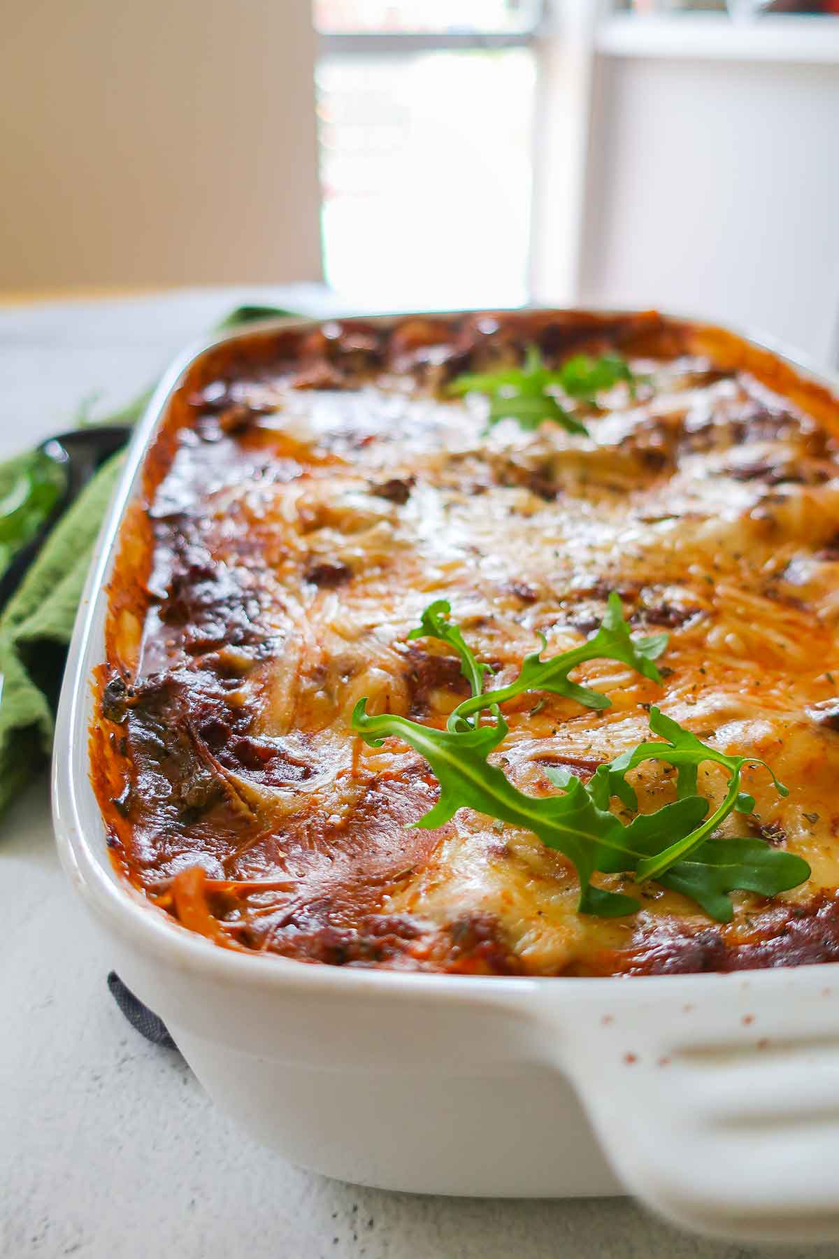 baked dairy free lasagna topped with arugula in a baking dish