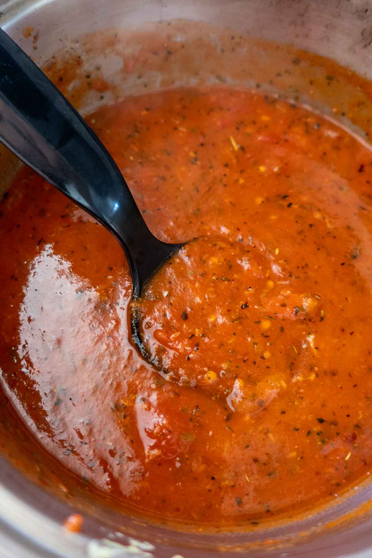 tomato sauce in a saucepan with a spoon