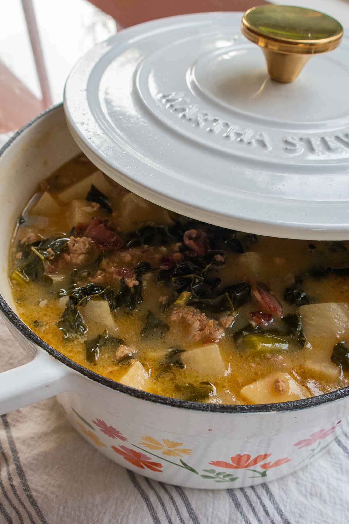 Dutch oven with zuppa toscana covered halfway with a lid 