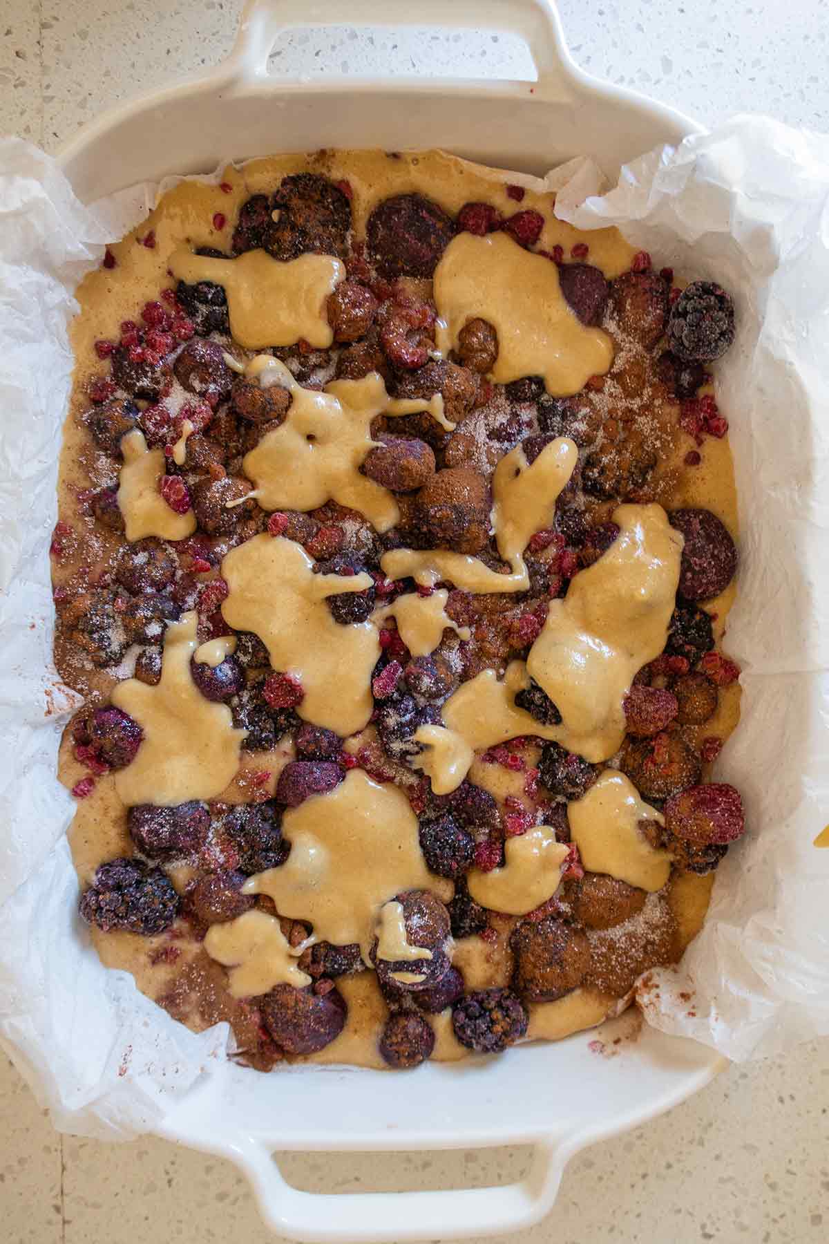 cake batter topped with frozen berries in a baking pan