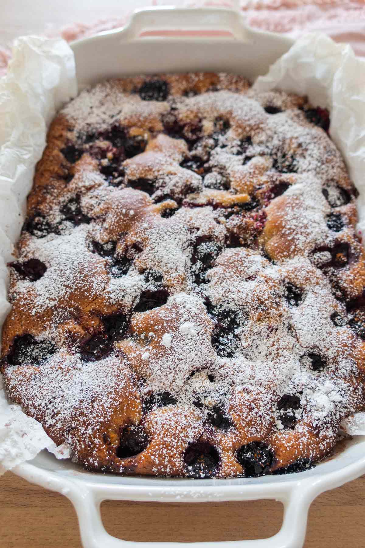 baked berry coffee cake dusted with powdered sugar in a pan