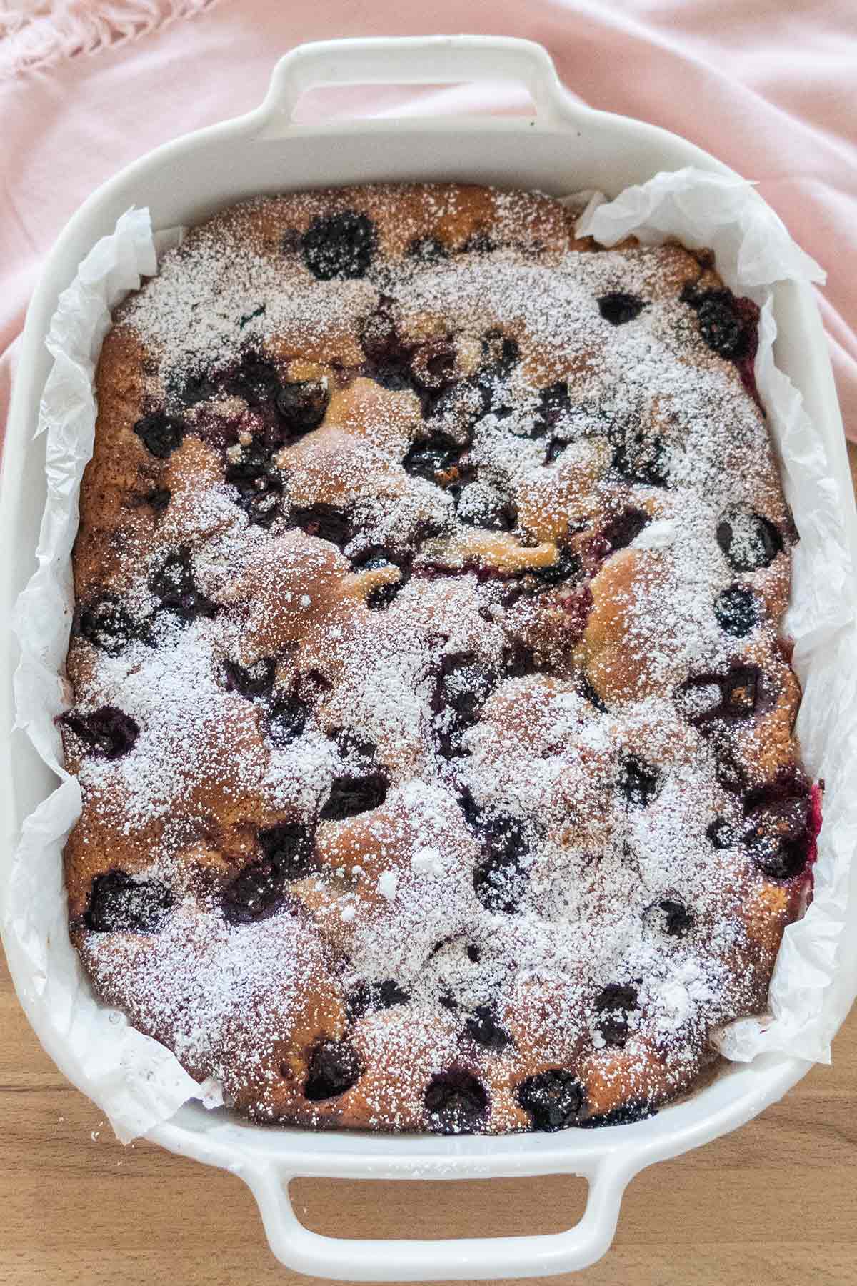 overview of a baked cake topped with powdered sugar in a pan