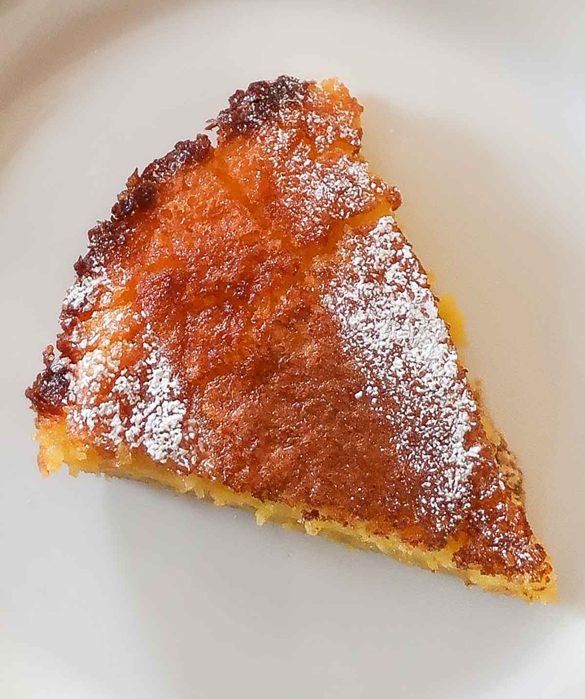 close up of a slice of chess pie dusted with powdered sugar on a plate