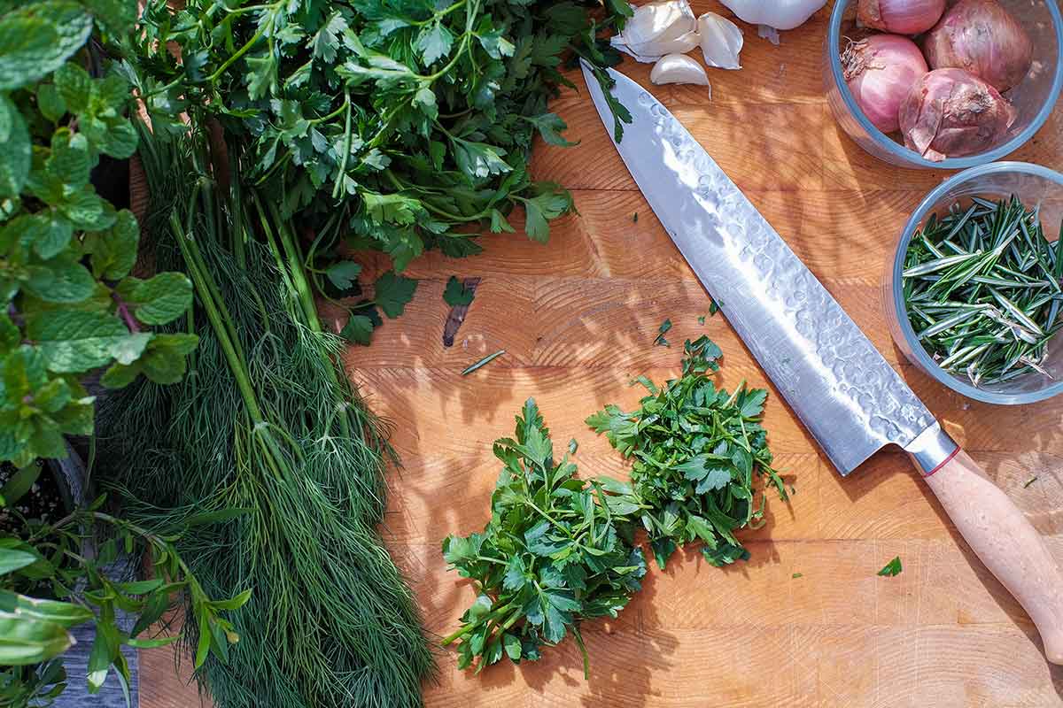 chopped fresh herbs with a knife on a cutting board