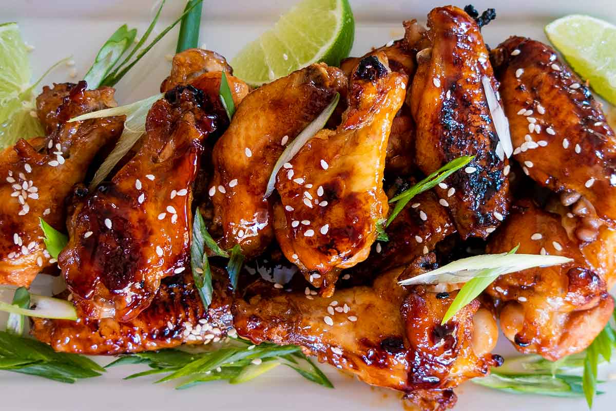 korean chicken wings on a platter with green onions