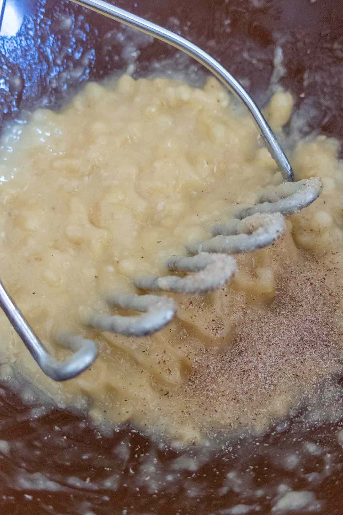 mashed banana with lemon juice in a bowl with potato masher