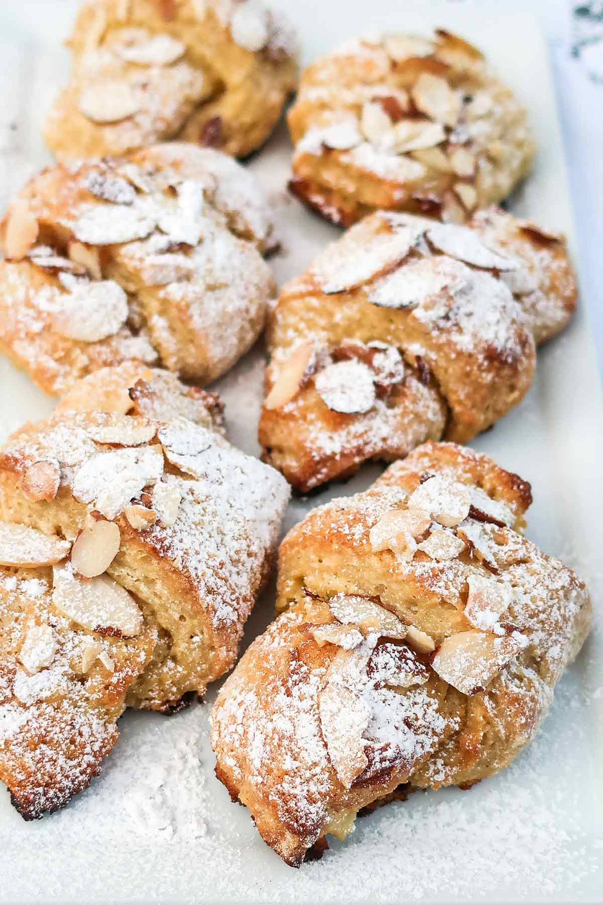 gluten free almond crescent rolls topped with sliced almonds and powdered sugar