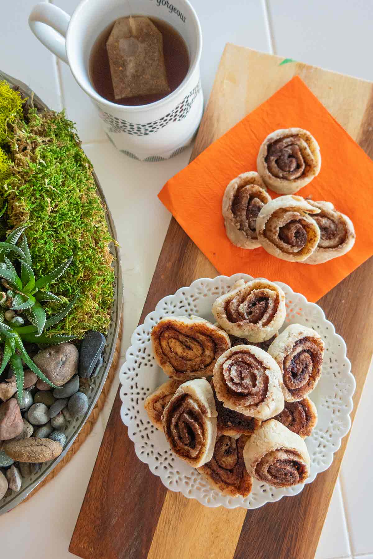 overview of cinnamon roll pie crust cookies on a plate with a cup of tea