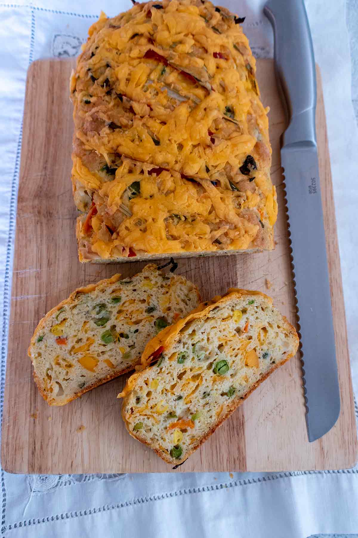overview of savory breakfast bread loaf with 2 slices on a cutting board