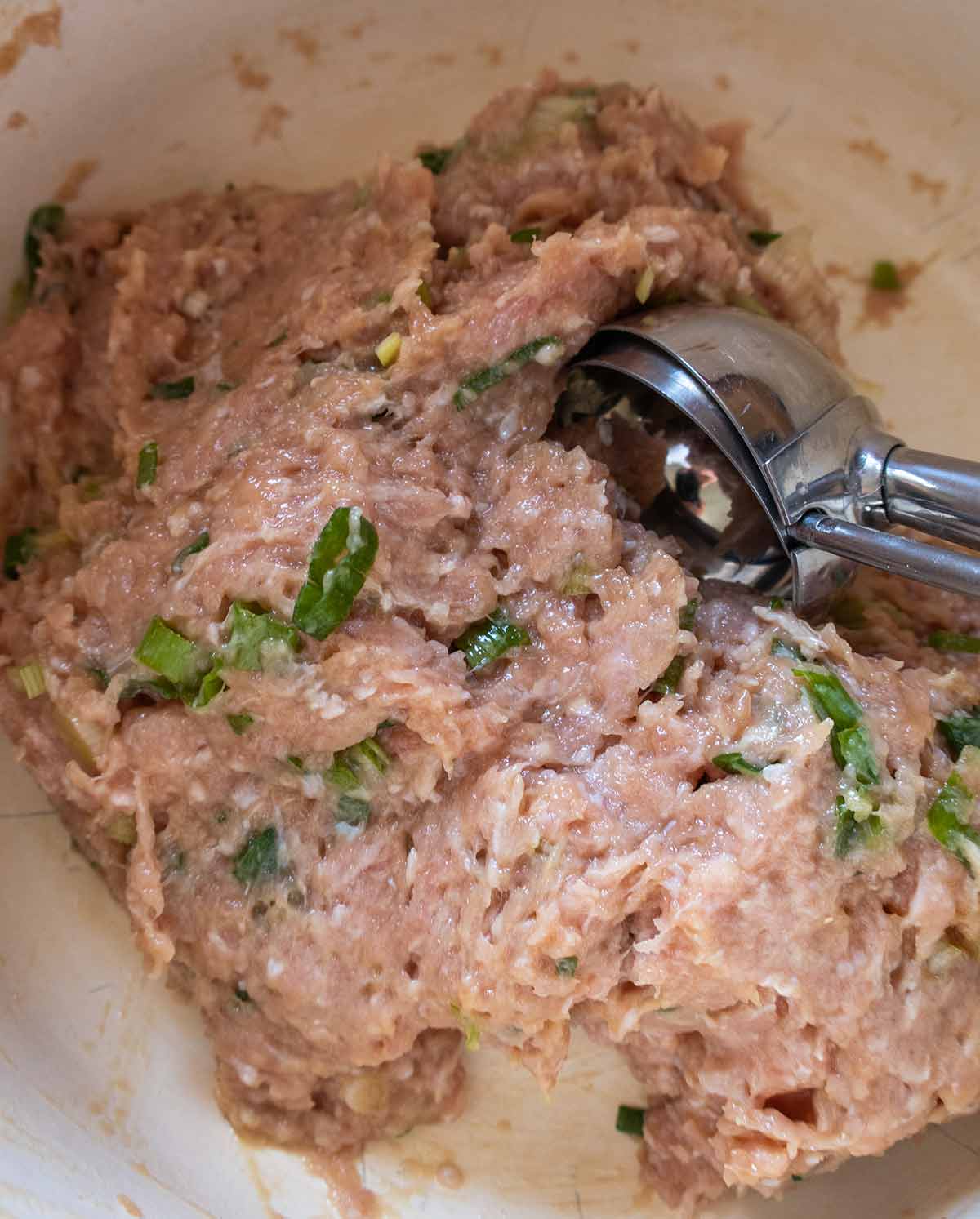 chicken filling for gluten free wontons in a bowl with ice cream scooper