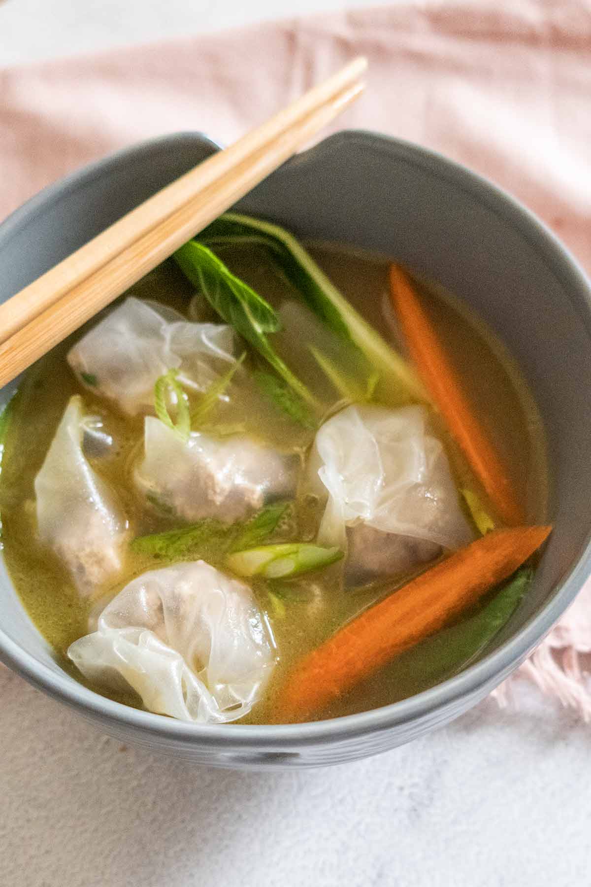 soup with dumplings and veggies in a bowl with chopsticks