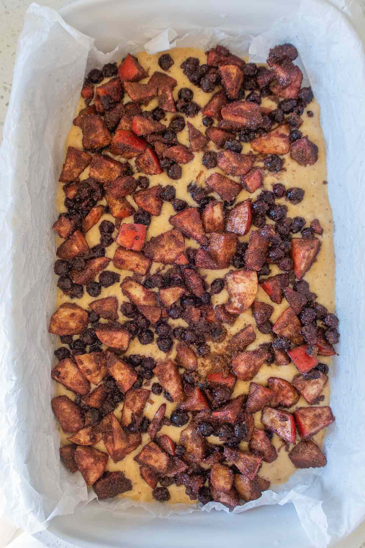 batter in a pan topped with cinnamon coated fruit