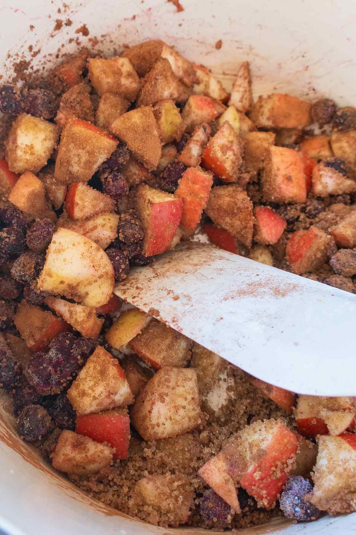 blueberries and apples in a bowl tossed with cinnamon and sugar 