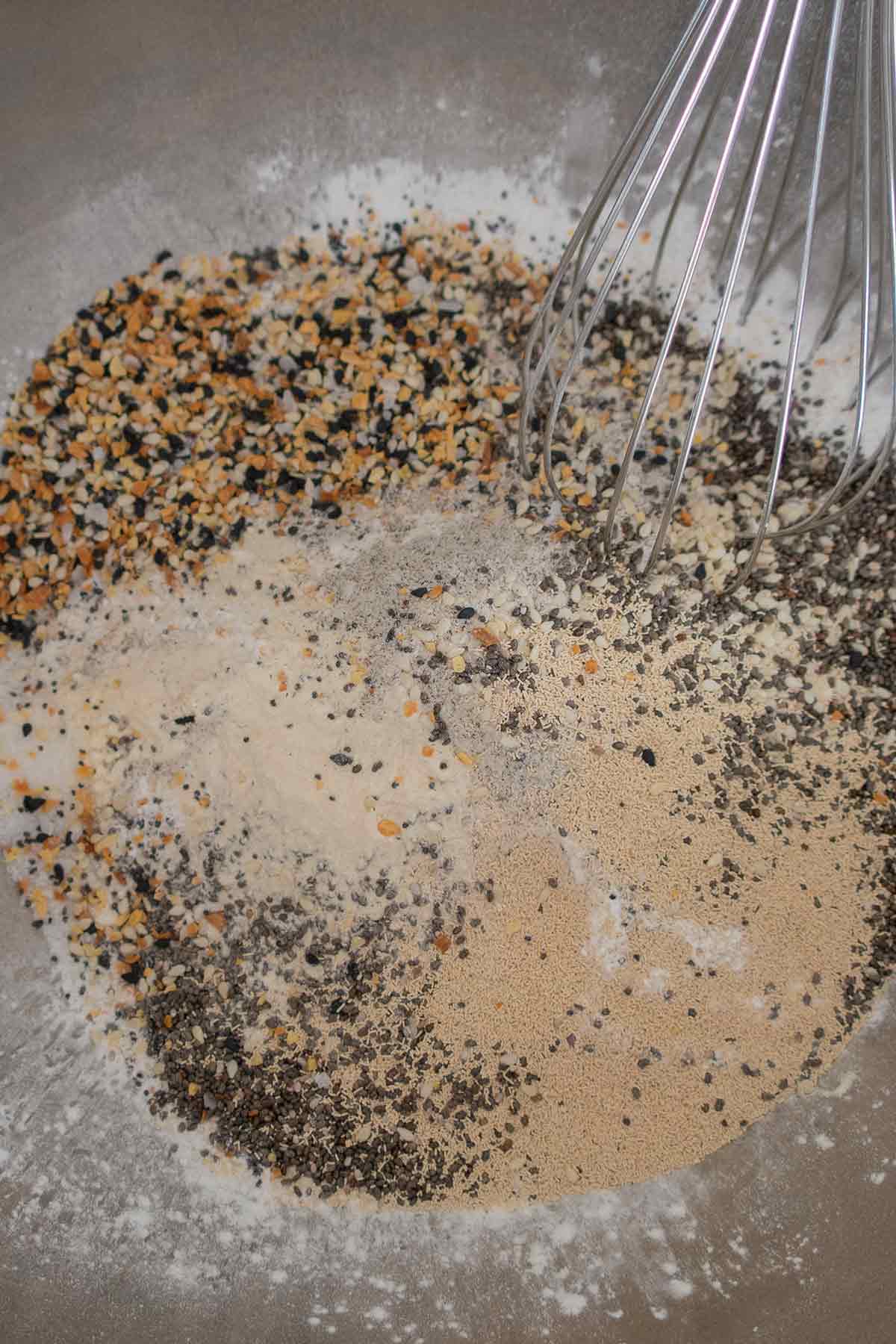 flours, seeds, yeast and xanthan gum in a bowl with a whisk