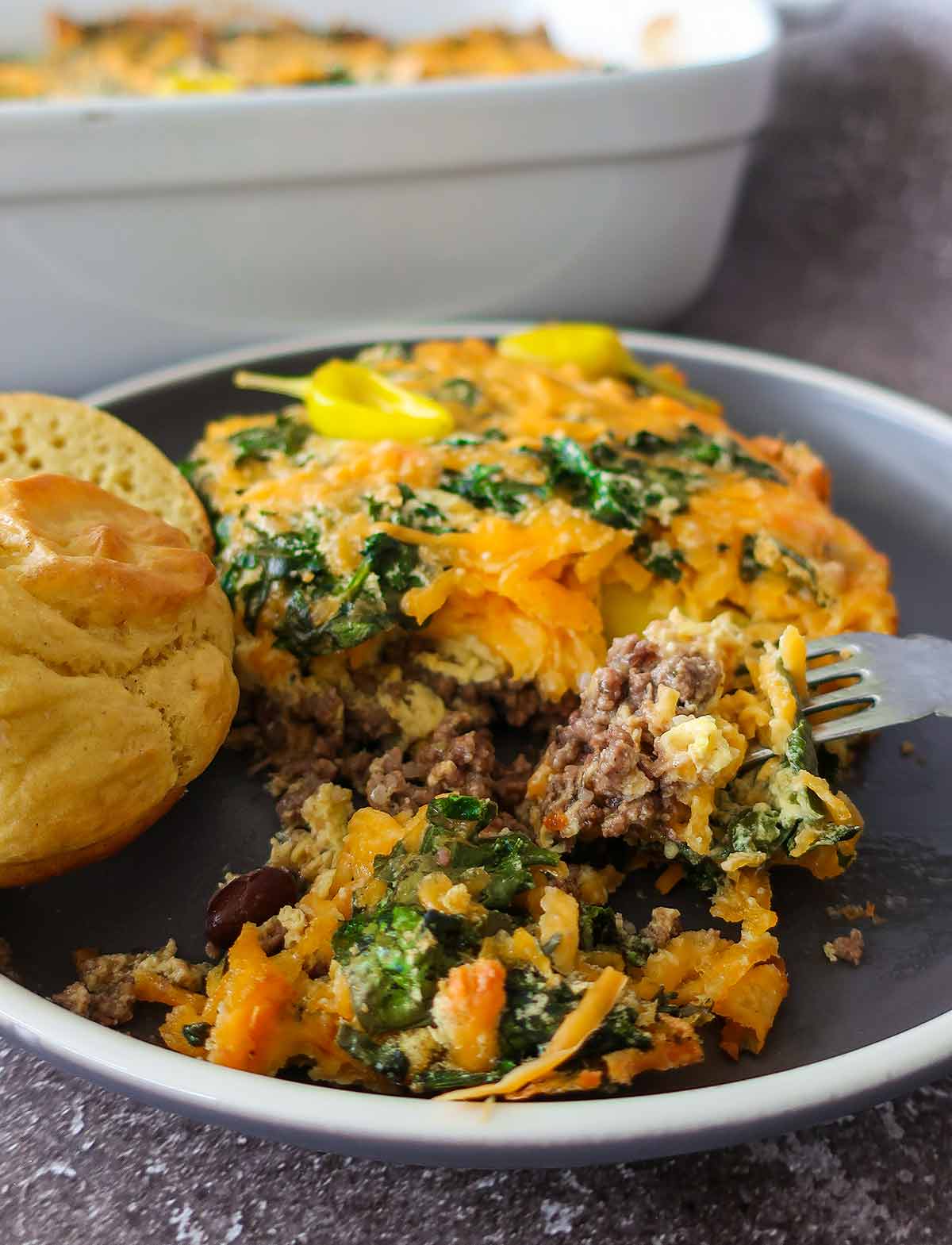 serving of john wayne casserole on a plate with rolls and a fork