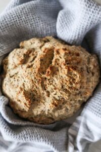 round loaf of gluten free peasant bread wrapped in a kitchen towel