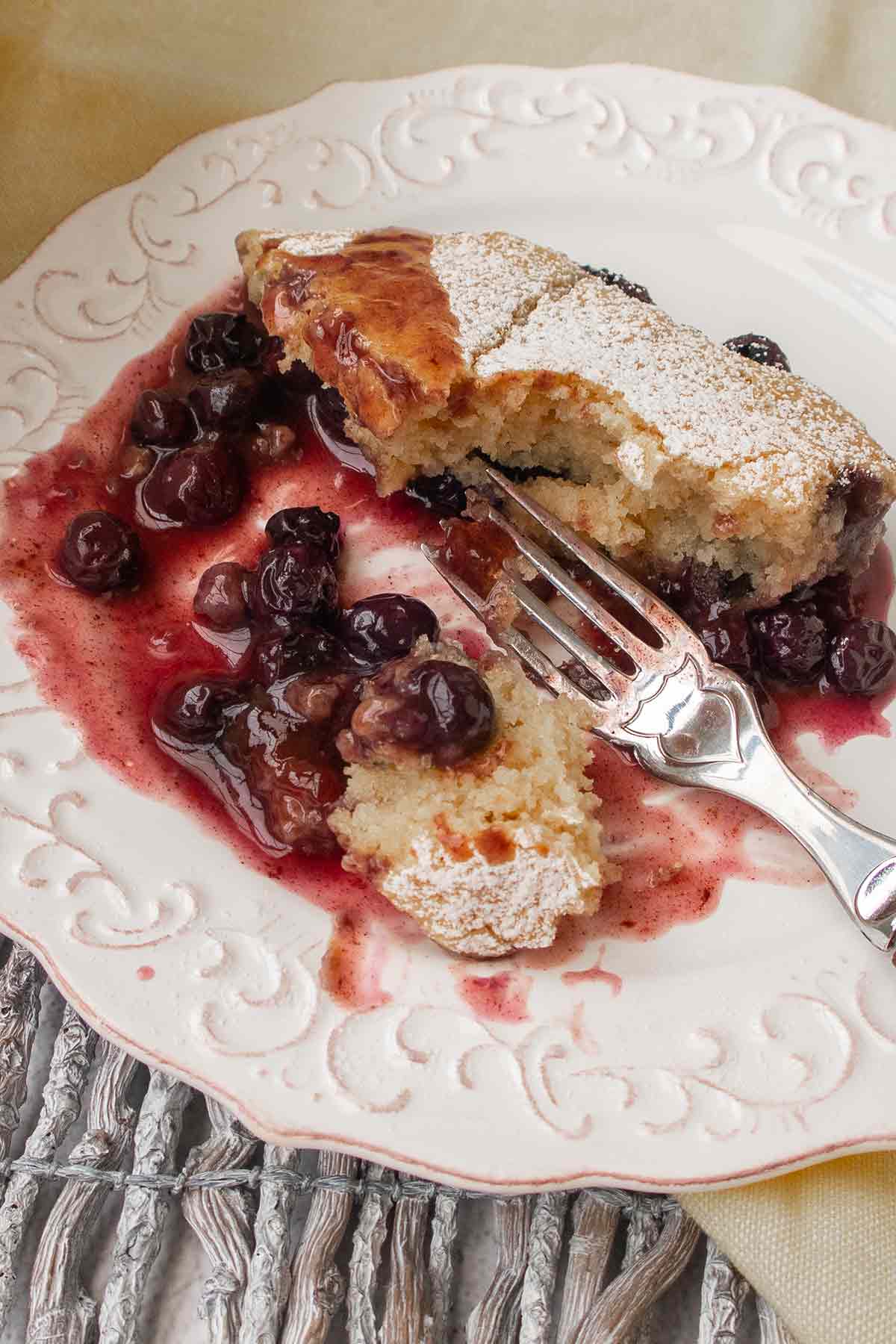 half eaten blueberry pudding cake on a plate with a fork