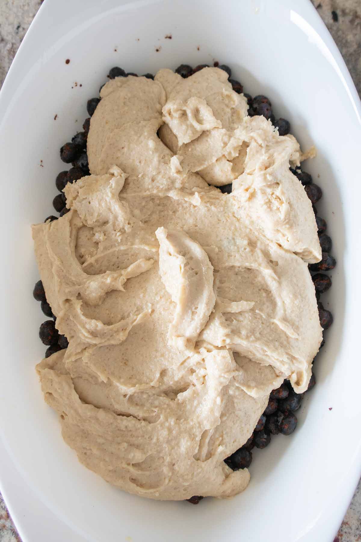 batter spooned over blueberries in a baking dish