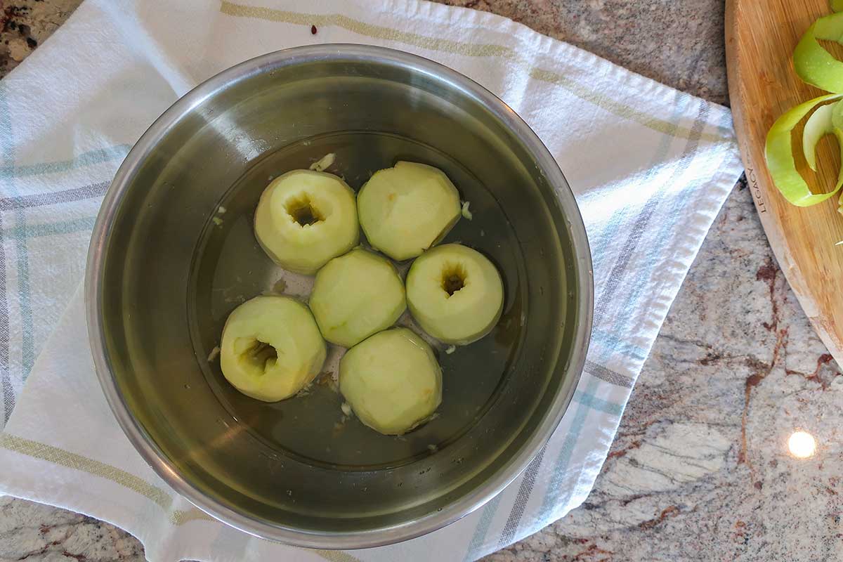 peeled cored apples in a bowl with water and lemon juice