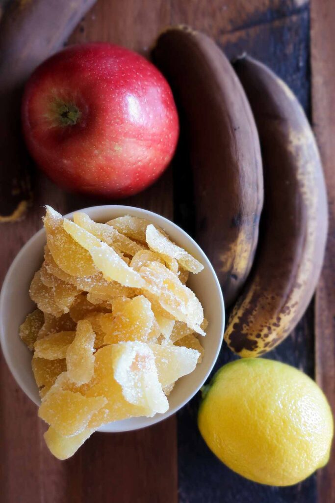 ripe bananas, crystallized ginger, lemon and apple on a wooden board