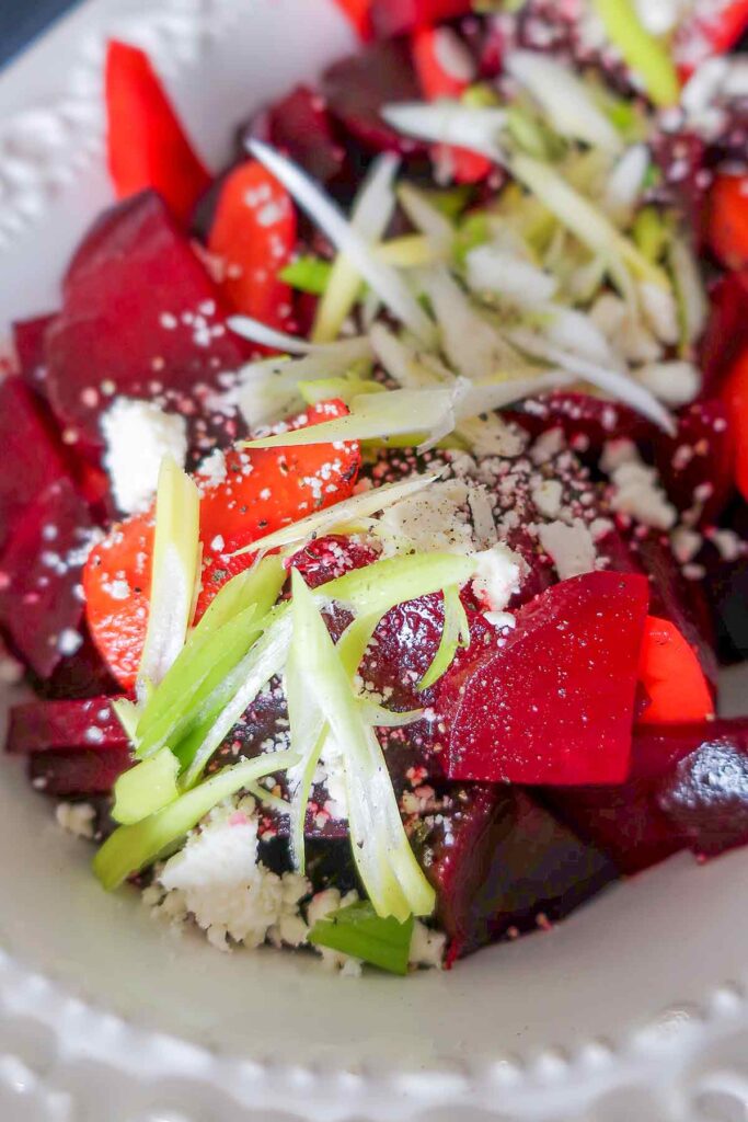 beet salad showcasing feta cheese, carrots and green onions on a platter