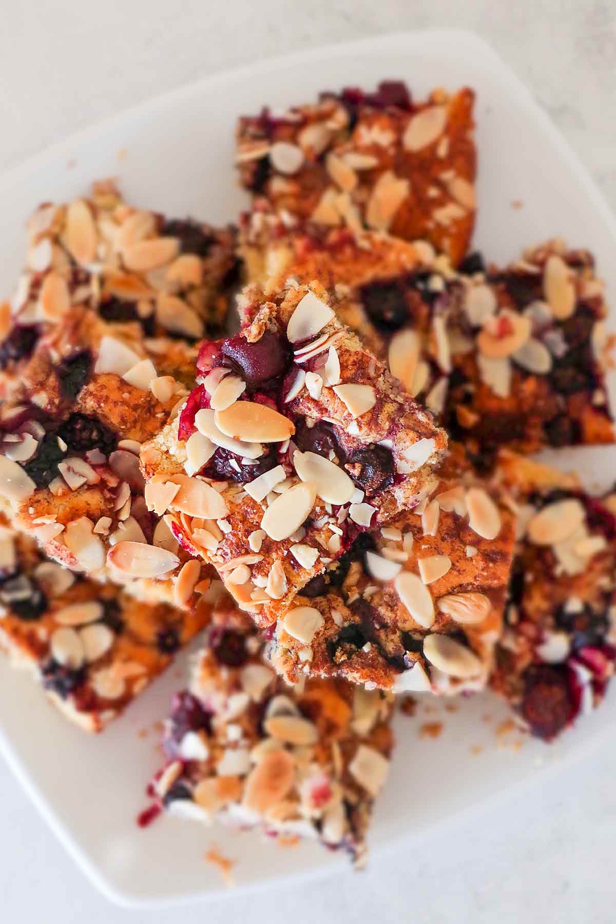 stacked pieces of gluten free fresh berry almond snacking cake on a plate