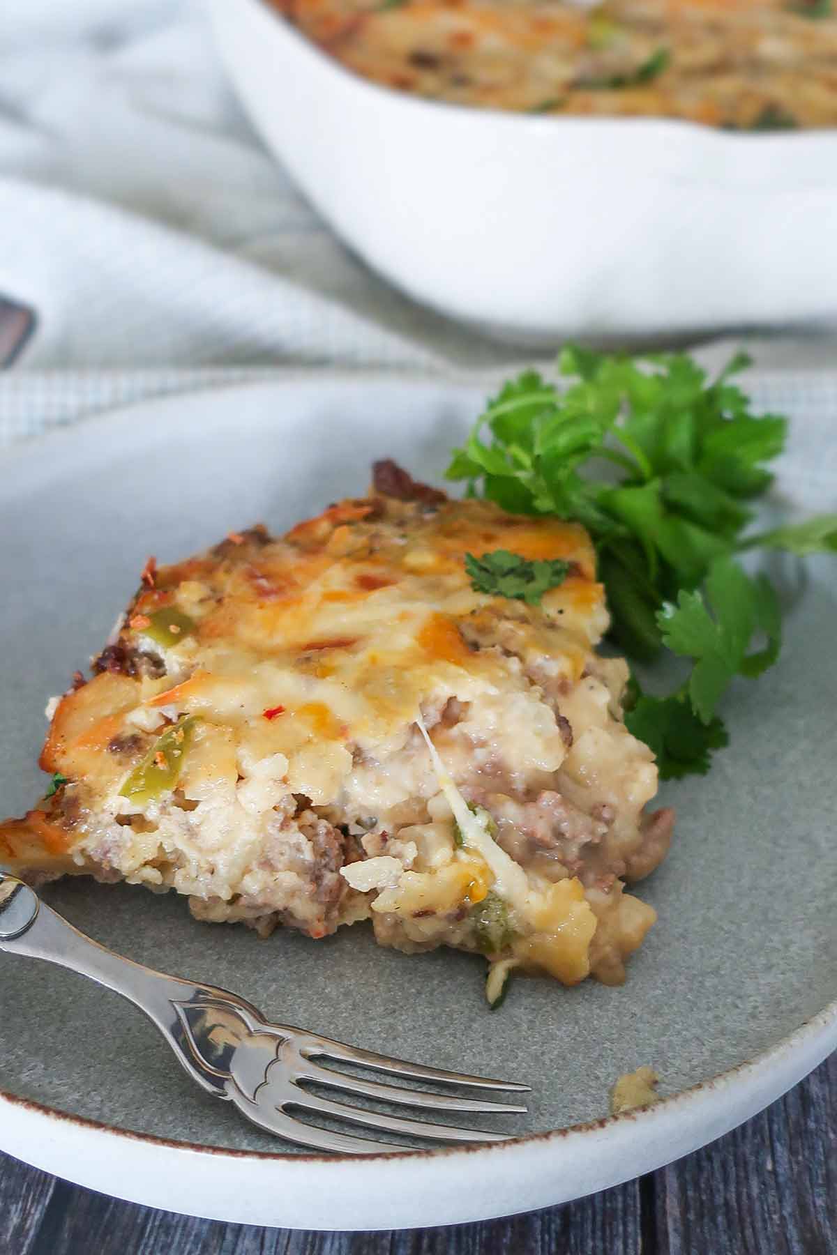 a slice of sausage breakfast casserole on a plate with a fork