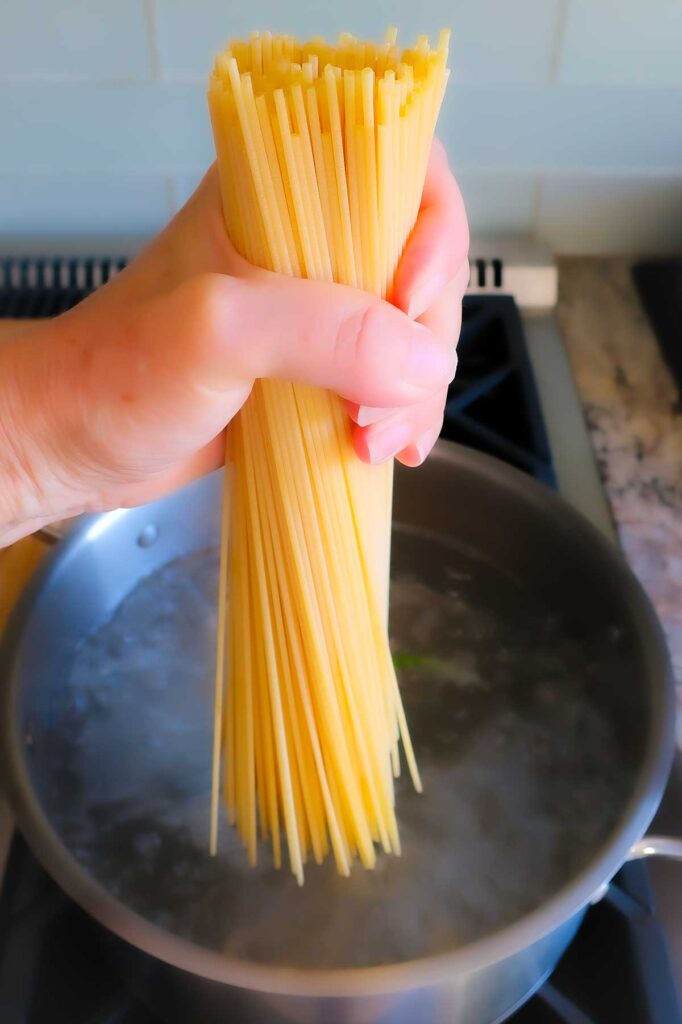 holding dry spaghetti pasta in a hand ready to drop into boiling water