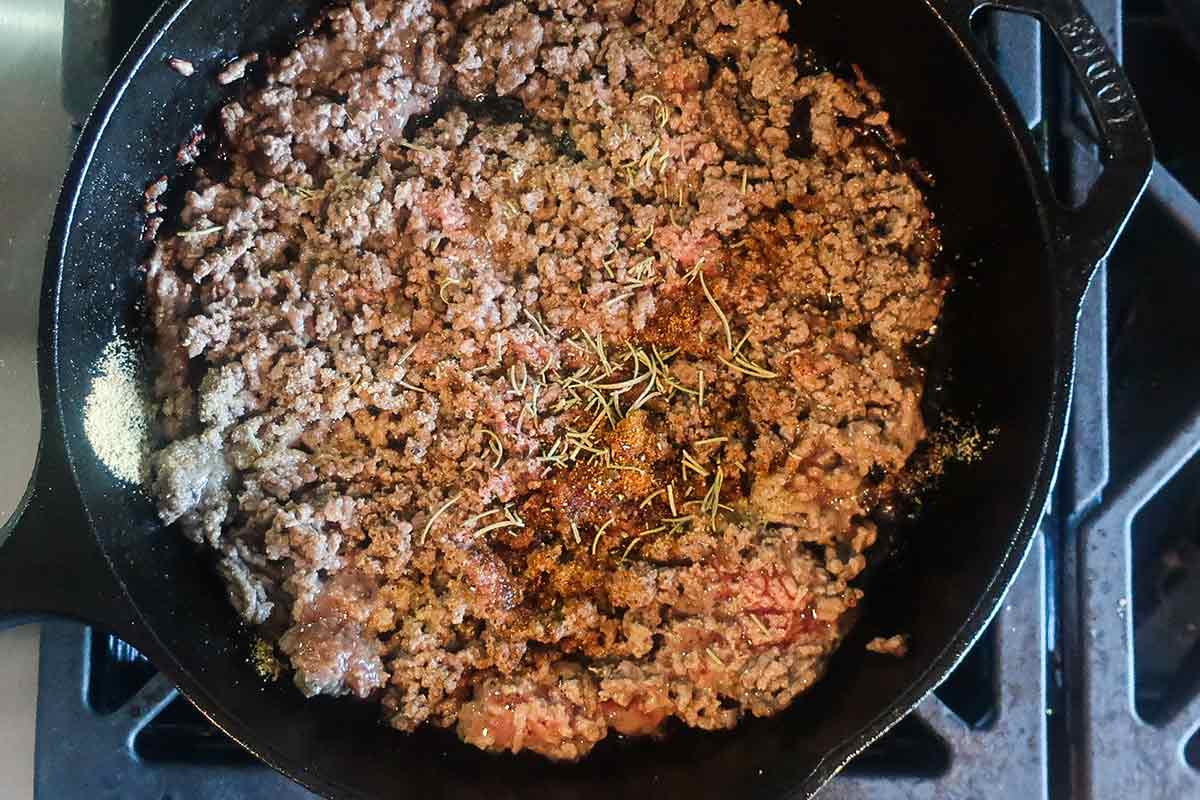 browning pork in a skillet with herbs and spices