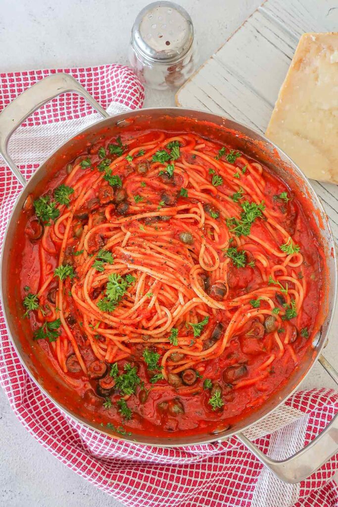 overview of pasta puttanesca topped with parsley in a large skillet