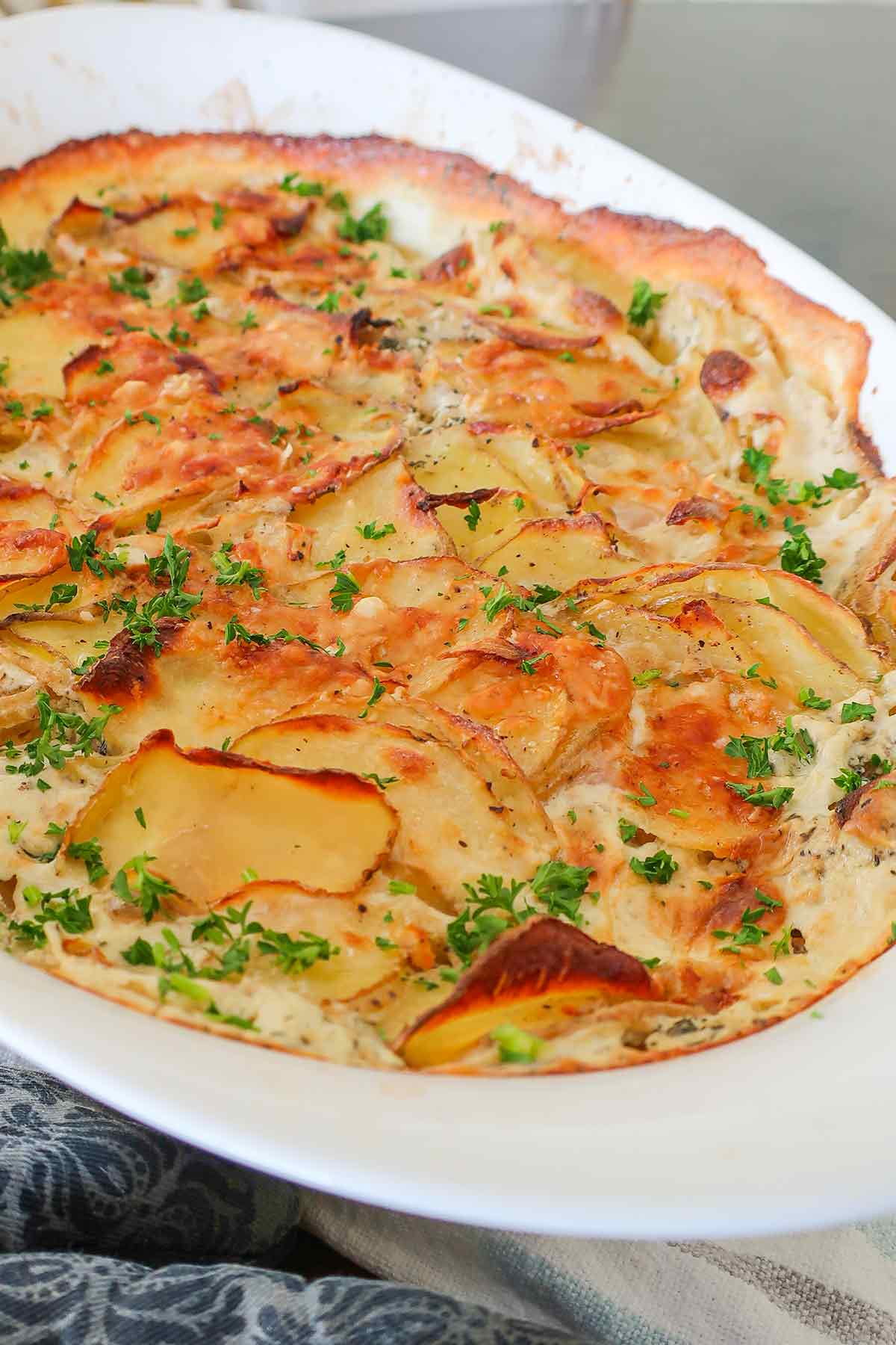 baked layered potatoes with onions with cream sauce in a casserole dish