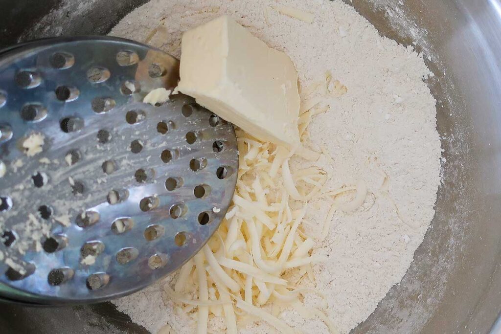 grating ice cold butter into flour