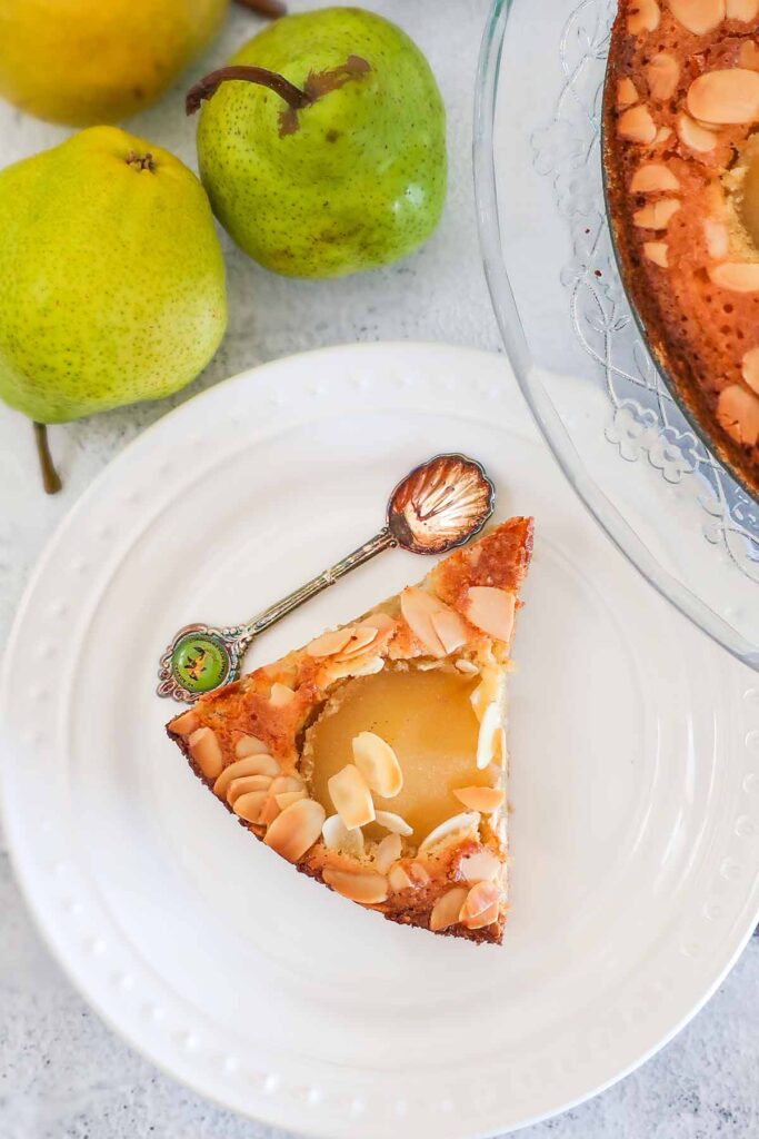 overview of a slice of pear and almond frangipane cake on a plate with a spoon