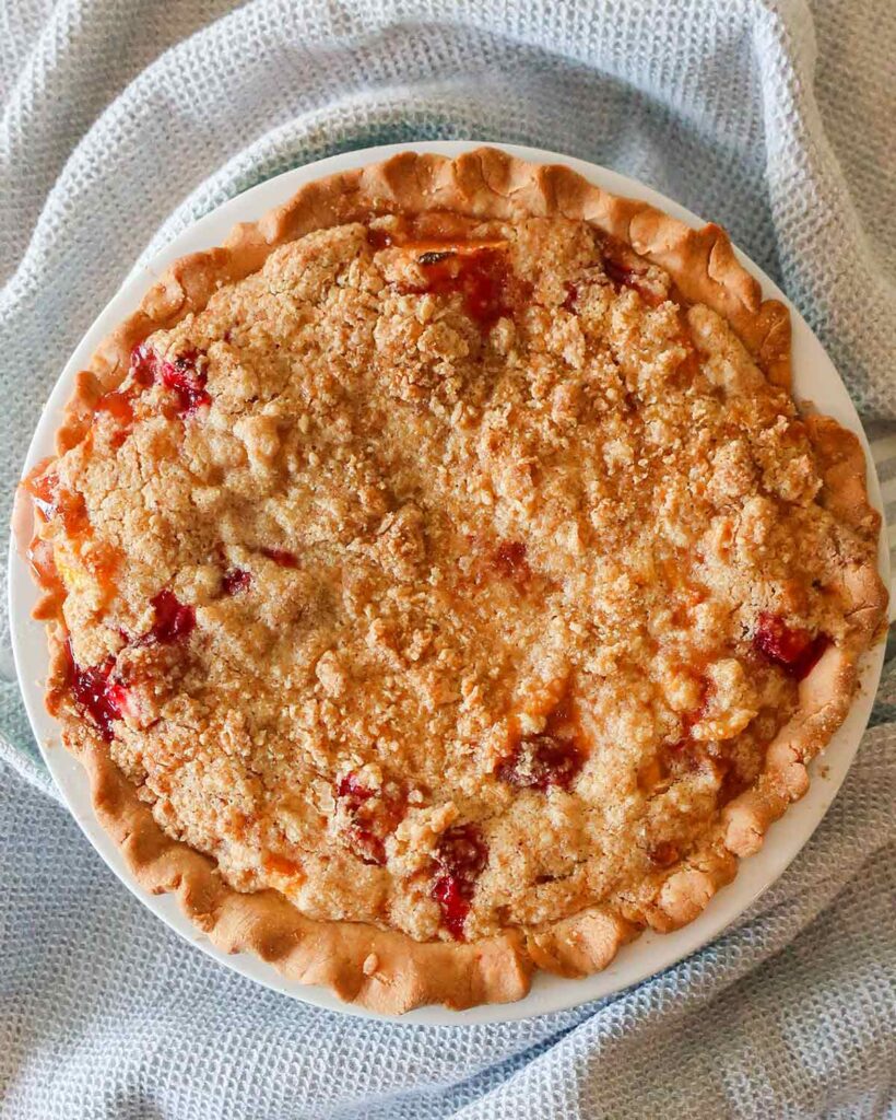 whole baked peach and strawberry pie in a pie dish