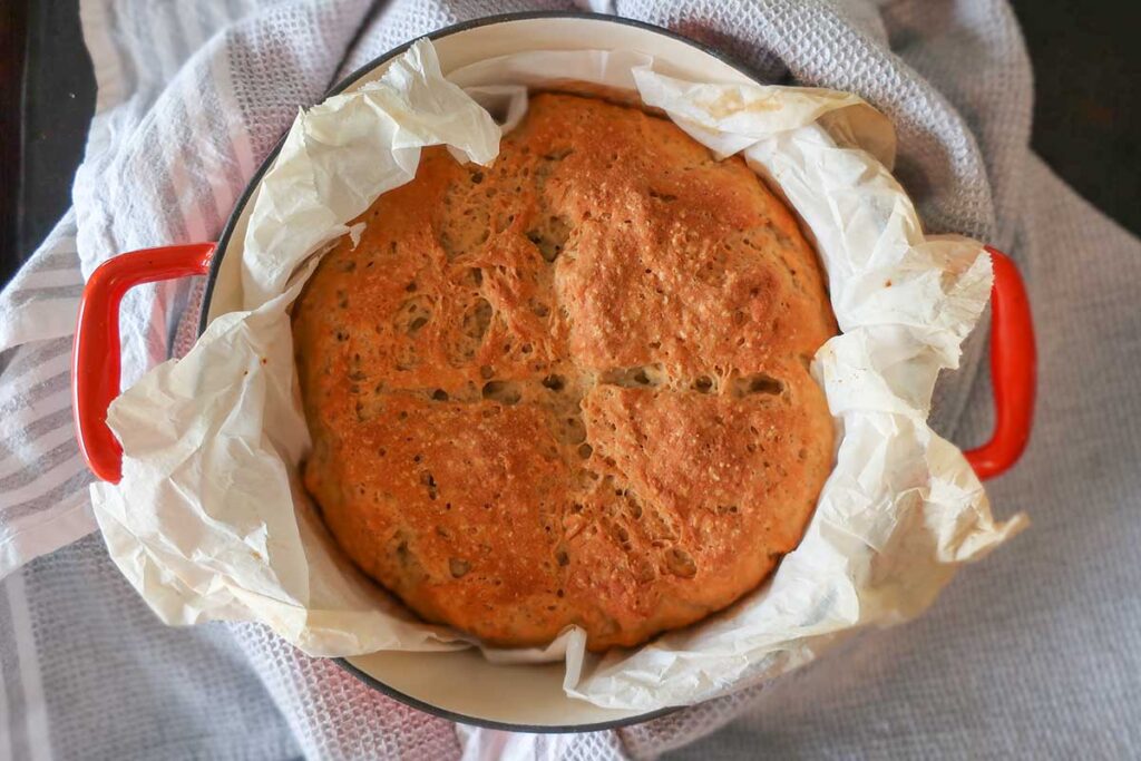 baked portuguese bread in a cast iron pot lined with parchment paper