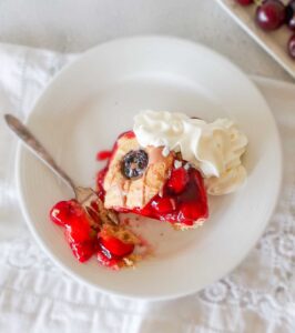 gluten free cherry cake with whipped cream on a dessert plate