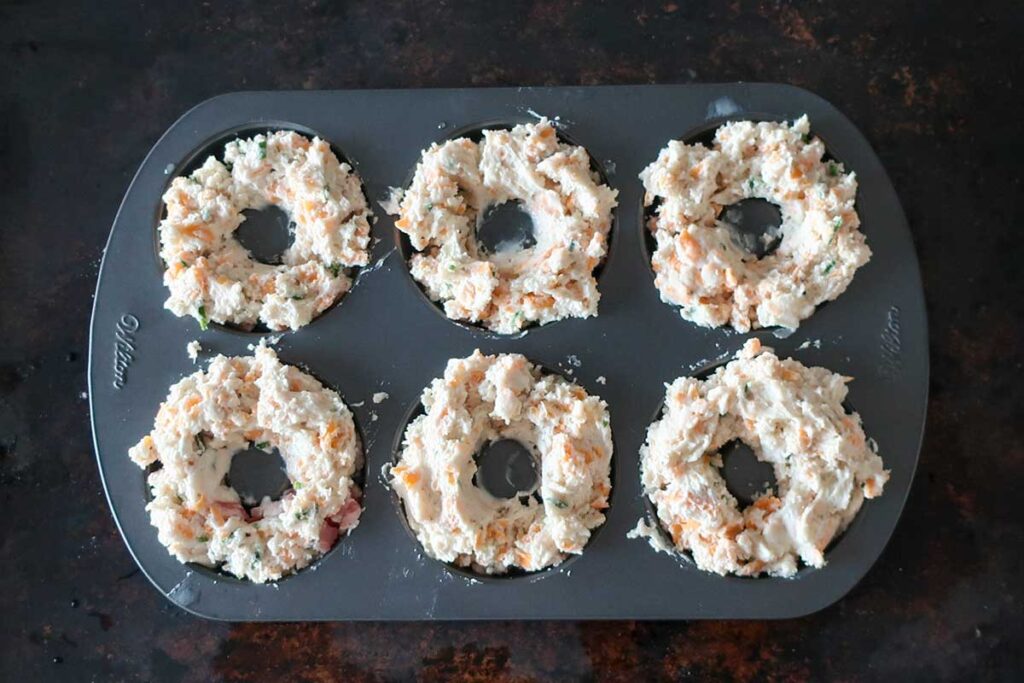 dough on top of bacon in a donut pan