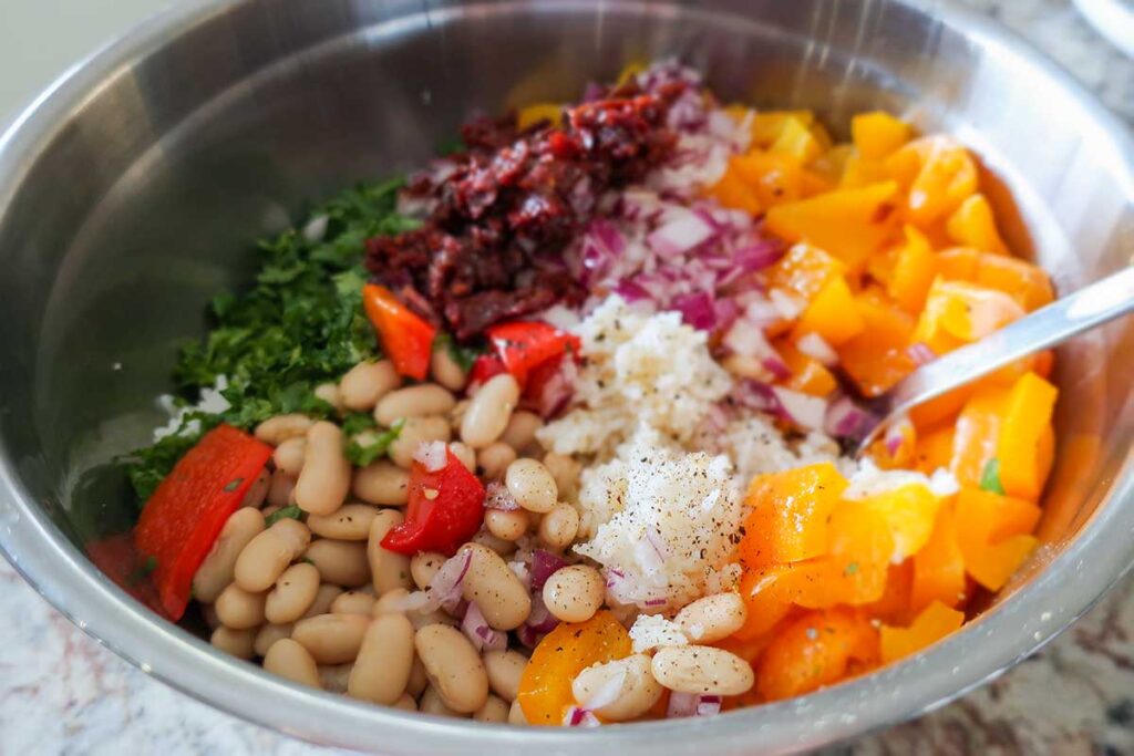 ingredients for roasted pepper white bean rice salad in a bowl