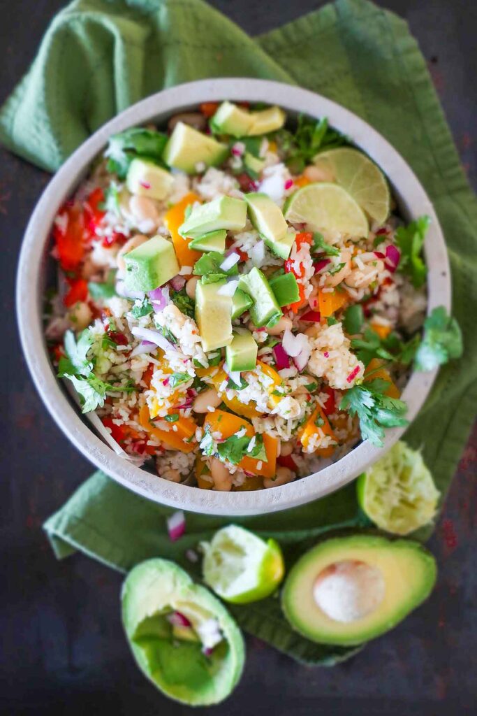 roasted pepper white bean rice salad topped with avocado chunks