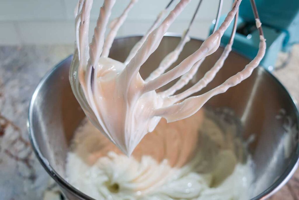whipped cream cheese with sugar in a bowl with a whisk