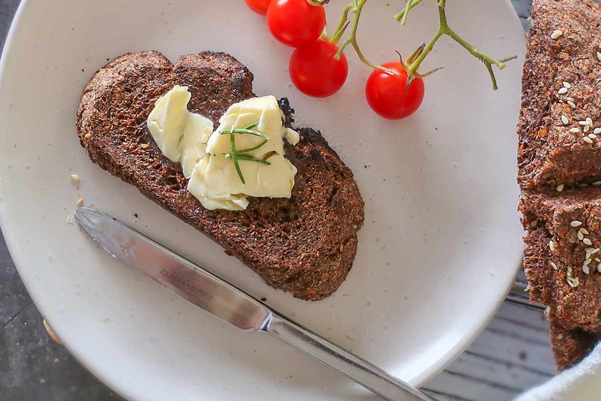 slice of toasted flaxseed bread with butte on a small plate