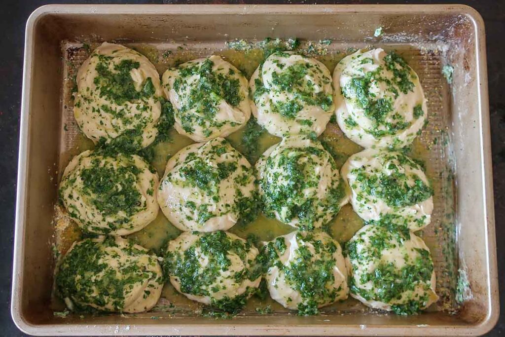12 mounds of dough brushed with garlic butter in a pan