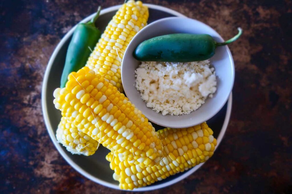 corn on the cob, jalapeno pepper and feta cheese in a bowl