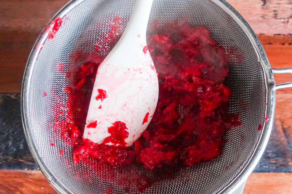 cooked cranberries in a fine mesh sieve