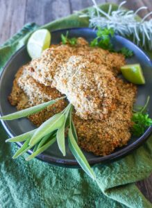 3 pieces of oven-fried buttermilk chicken garnished with herbs on a plate, gluten free