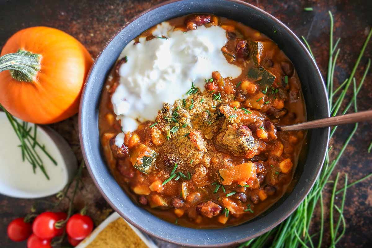 bowl of vegan pumpkin chili with a miniature pumpkin on the side